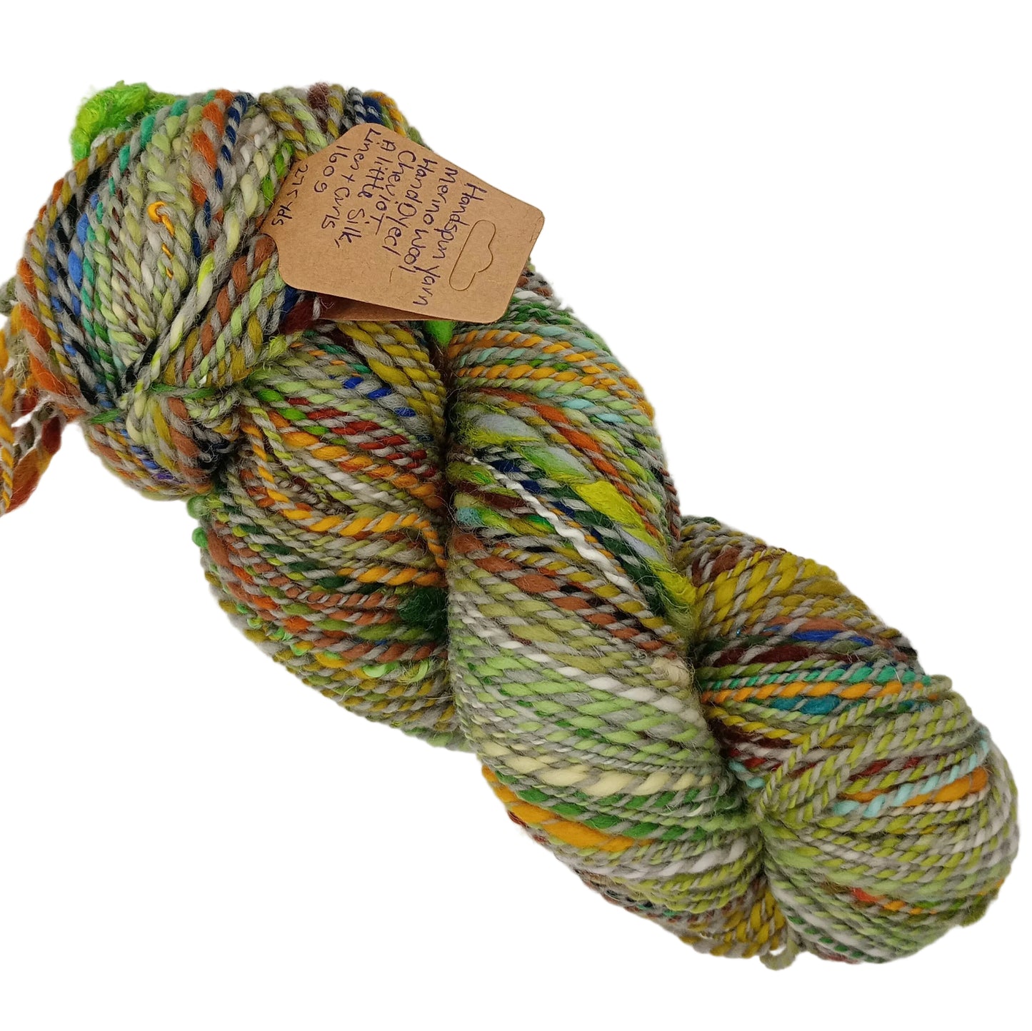 A skein of variegated yarn with mixed colors including green, yellow, orange, brown, and cream, featuring a small kraft paper tag attached, set against a plain white background.
